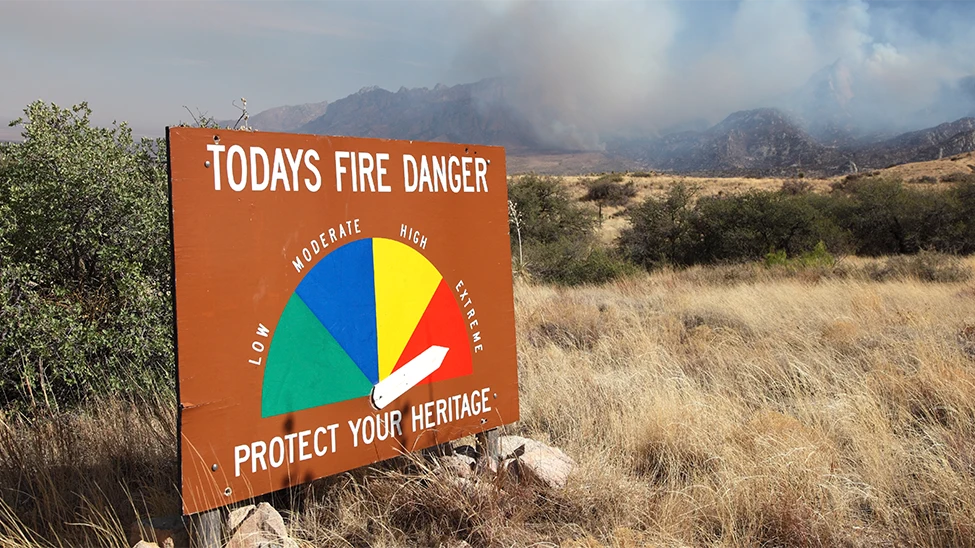 A sign shows high fire danger by an open field