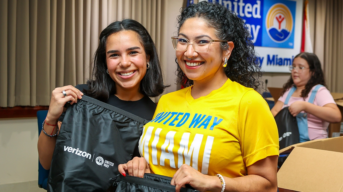 Two United Way of Miami staffers smiling as they hold emergency preparedness kits