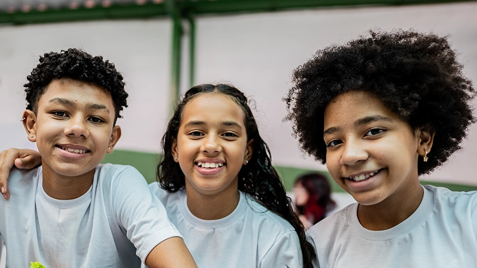 Three kids smiling and hugging each other