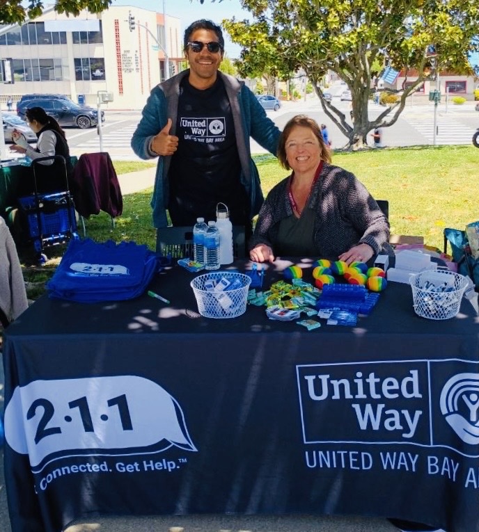 a man and woman at a UWBA and 211 table