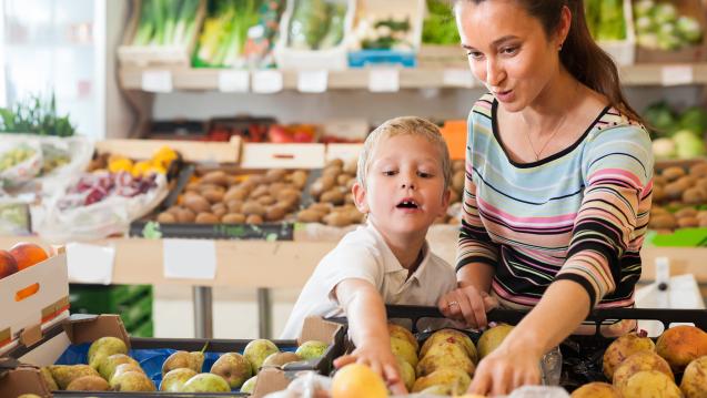 Mother and young son pick out fruit in a market