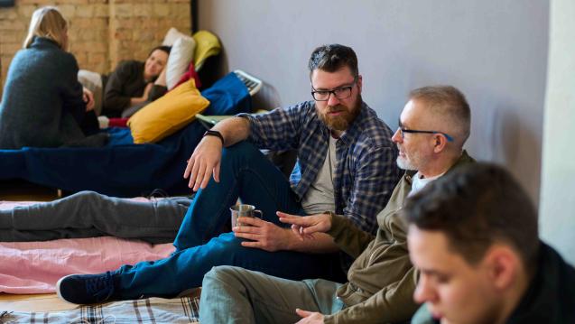 Individuals sitting on the ground at a temporary shelter