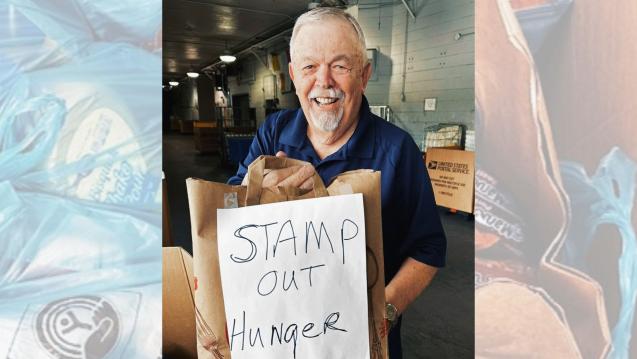 Man with bags of donated items and sign that reads "Stamp out hunger"