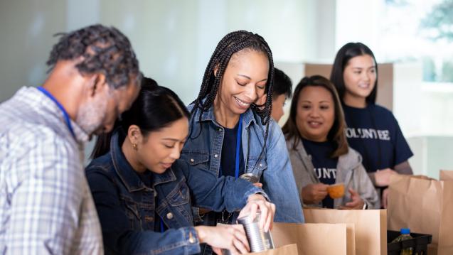 Young adult volunteers packing food items into bags 