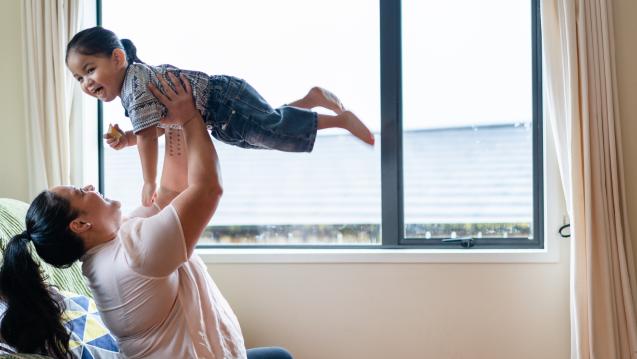 Woman holding a child in the air happily