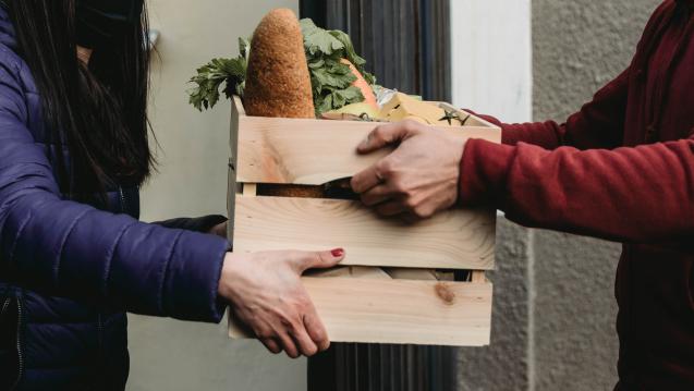 Two individuals exchanging a crate of food