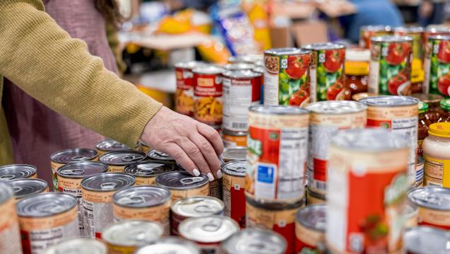 A woman selects canned goods at a food distribution location.