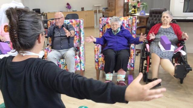 Participants in a chair yoga class open their arms