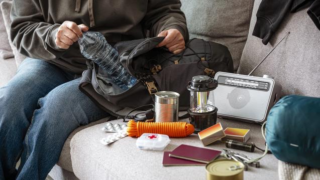 A person stuffing a water bottle in a go bag.