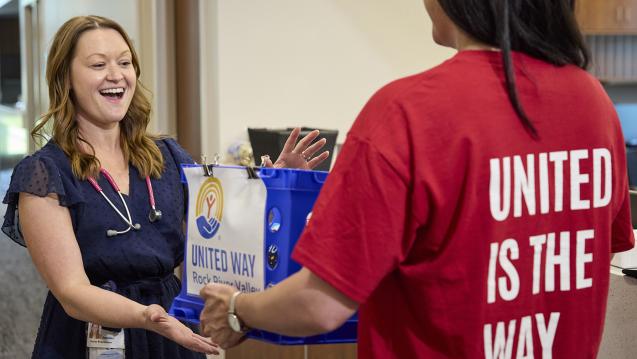 United Way volunteer hands a United Way-branded bag to a smiling woman