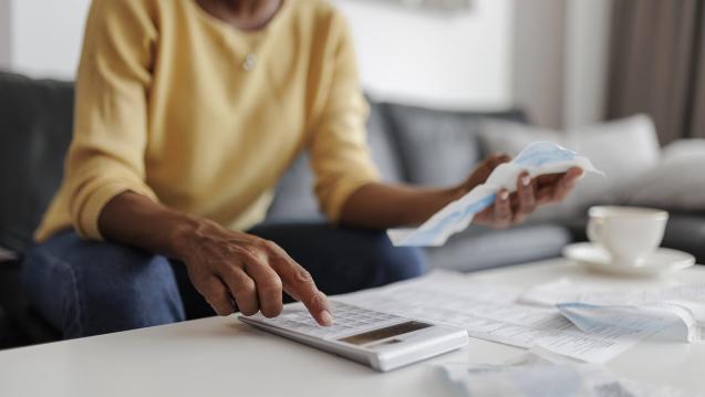 A person holds a bill and types into a calculator