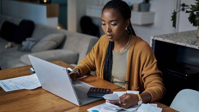 A woman sitting at a table looking at her laptop