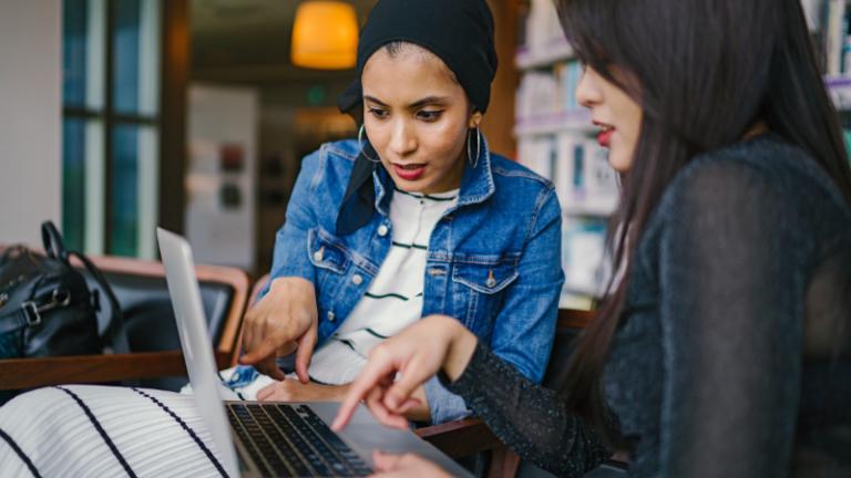two women looking at computer screen collaborating