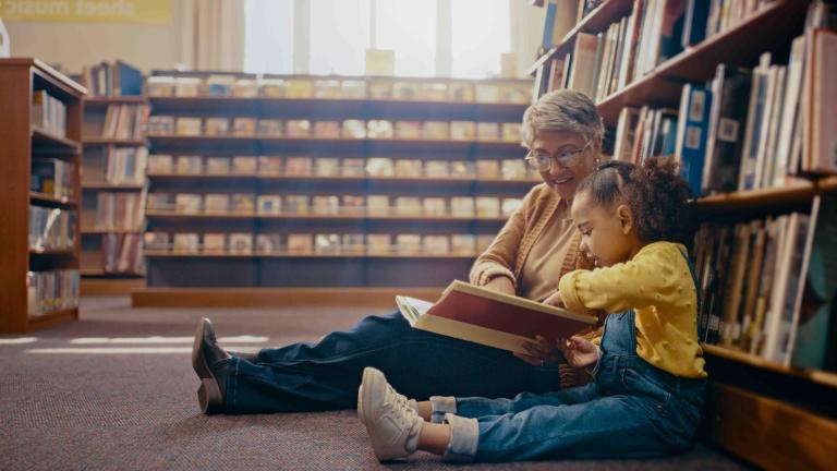 Women reading a book with a small child on the floor of the library