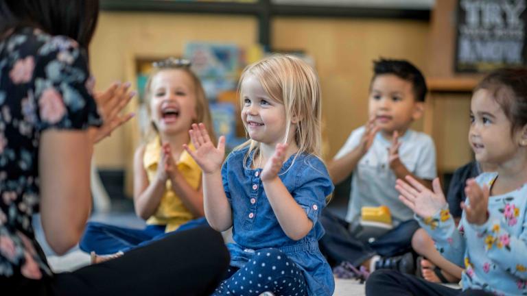 Children in a classroom clapping and playing