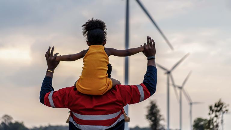 Girl on man's shoulders in a field of windmills