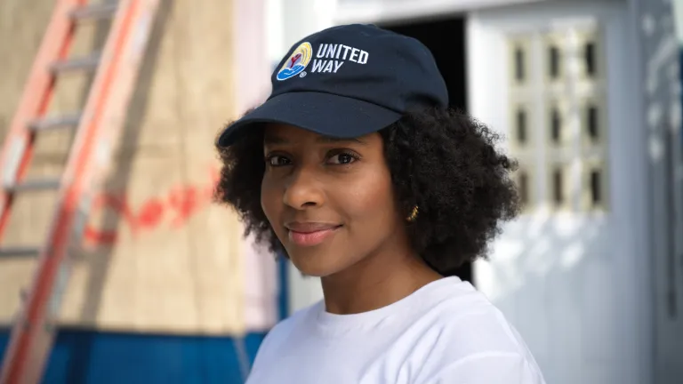 Woman in white shirt and black hat with United Way logo