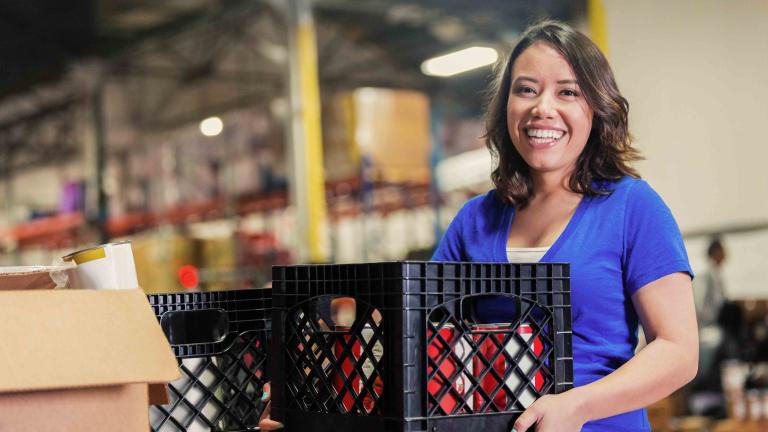 volunteer holding a crate with donated food items