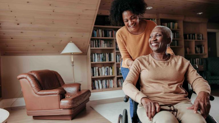 Woman pushing an elder in a wheelchair in a home