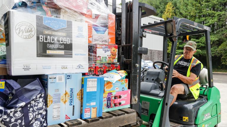 A volunteer driving a forklift loaded with donated goods