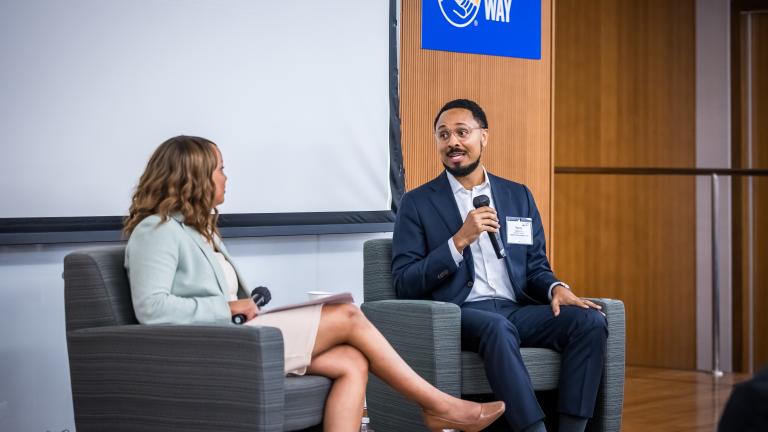 Two individuals seated on the stage of the Mary M. Gates Learning Center