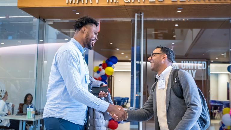 Two men shaking hands by the Mary M. Gates Learning Center