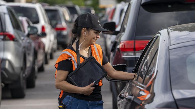 Woman speaking to driver of a car in line at a food pantry