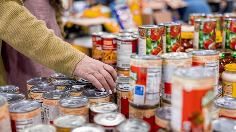 A woman selects canned goods at a food distribution location.