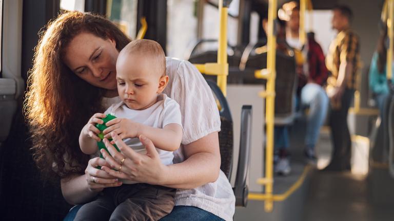 Woman holding child on lap while riding a bus