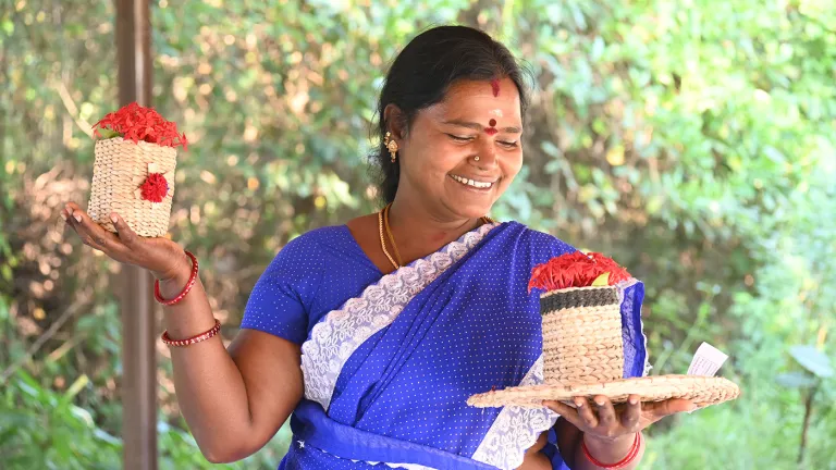 A woman in a blue sari holds woven products