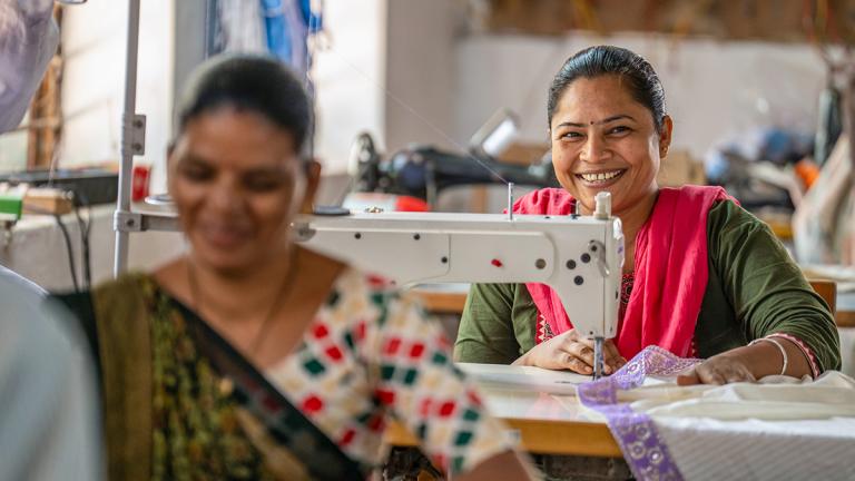 Two women smiling while working at sewing machines