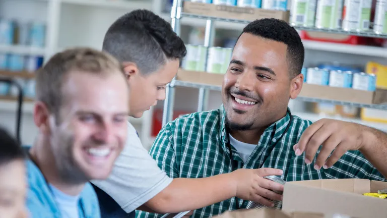 A man smiling while sorting groceries with child