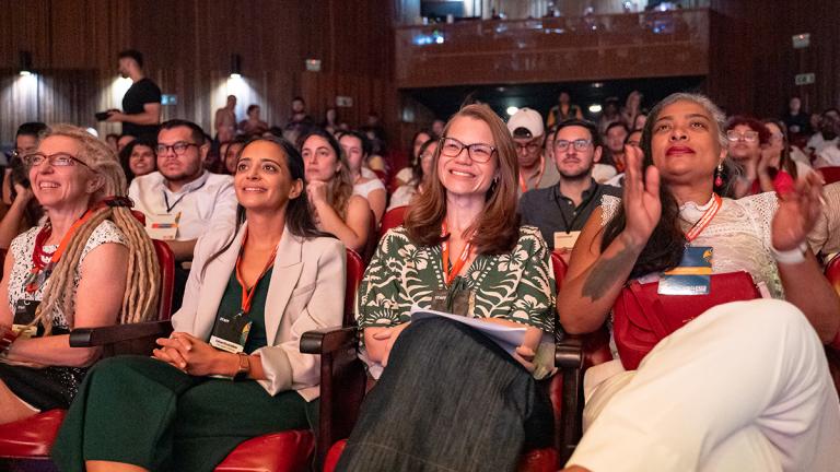 Attendees of the GOYN conference sitting in the audience, smiling and clapping. 