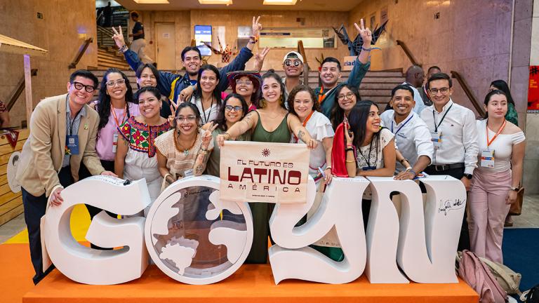 A group of attendees of the GOYN conference standing behind a sign that reads GOYN. 