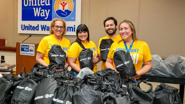 United Way Miami staff smiling as they fill emergency preparedness kits