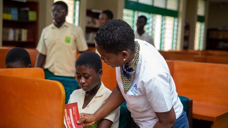 Students sitting a tables, reading books.