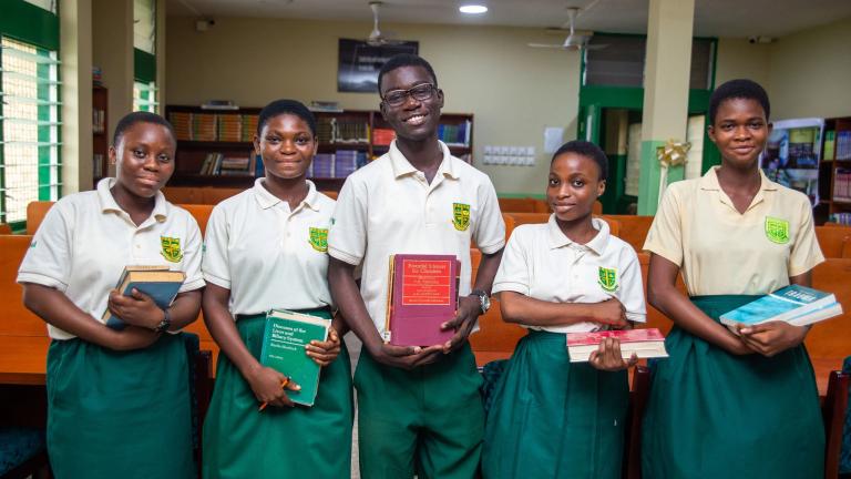 Five students smiling and holding books 