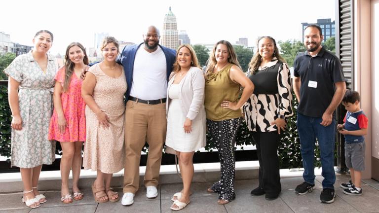 A group of seven scholars posing on a terrace with program coordinator Napthali Bryant
