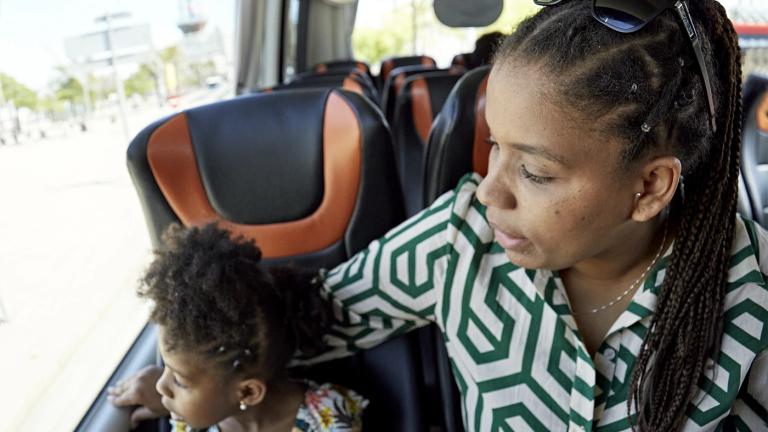 A woman and small child riding a bus and looking out of a window