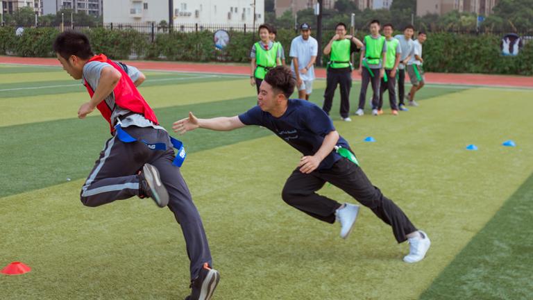 A young man attempts to full a flag off another player in a flag football demonstration that's part of a United Way initative in China