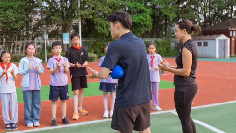 A man and a woman coach explain flag football to young students in China as part of the United Way and NFL inititative in C