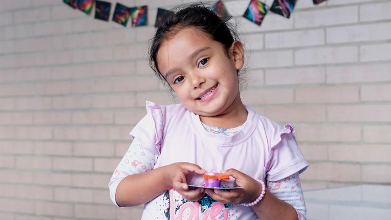 Emily, a five-year-old student at United Way Colombia's learning center in Bogotá's Bosa neighborhood, holding artworka 