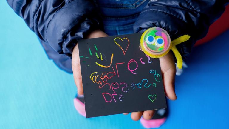 A child's hands holding artwork created at Cat Ojo de Perdiz Preschool, where United Way Colombia supports early learning and development