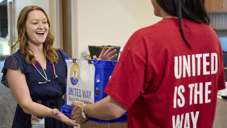 United Way volunteer hands a United Way-branded bag to a smiling woman