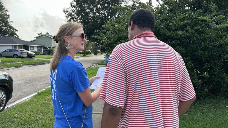 A woman with United Way of Southeast Louisiana holds a clipboard as she talks with a local resident