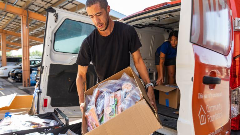 A United Way volunteer loads heat relief kits into a van for distribution