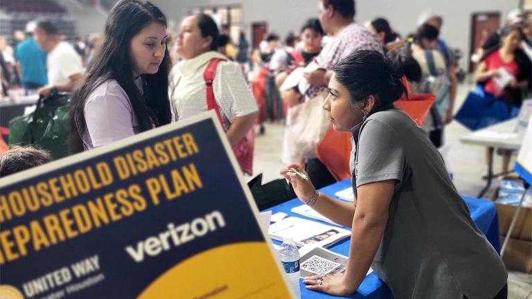 A woman stands at a table getting help while attending a United We Prepare Disaster preparation Workshop in Houston