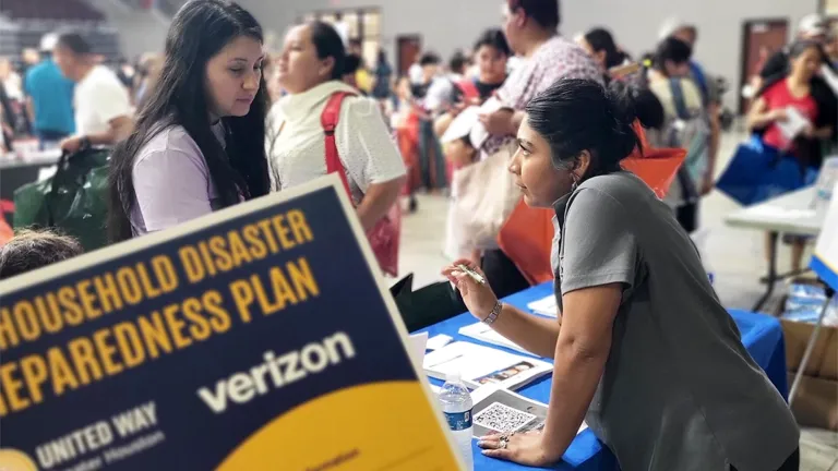 A woman stands at a table getting help while attending a United We Prepare Disaster preparation Workshop in Houston