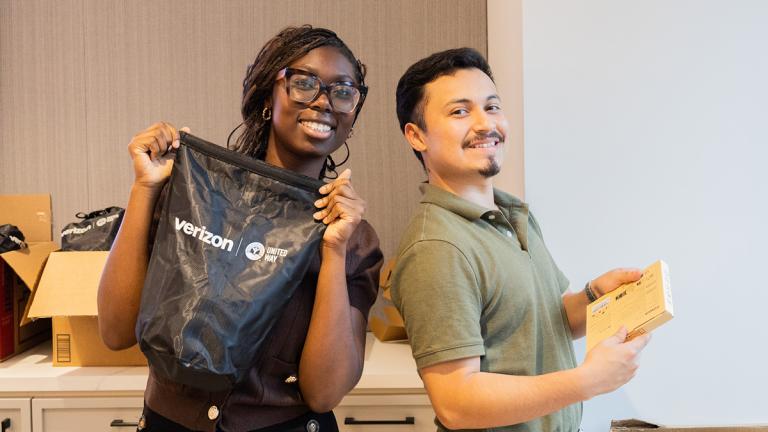 A woman holds up an emergency kit and a man holds preparedness materials