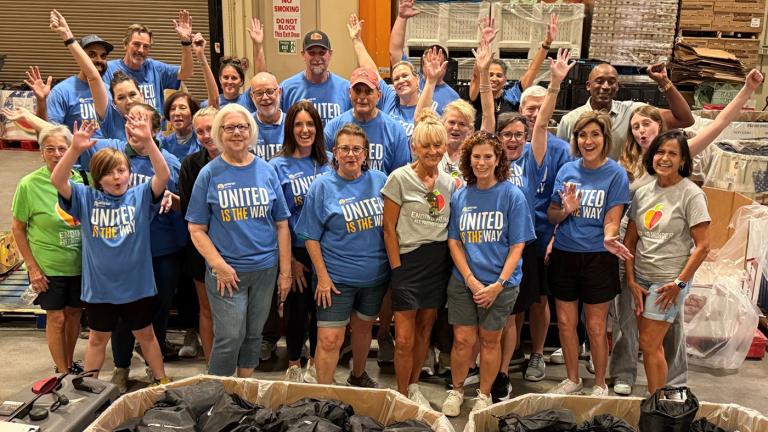 A group of 25 United Way Suncoast Volunteers standing and cheering 